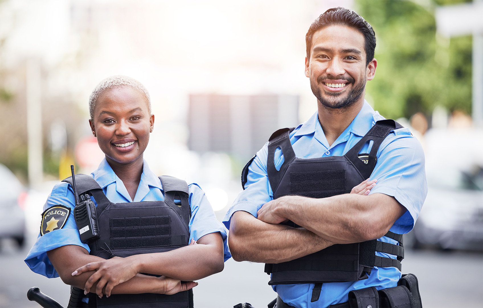 Two police officers standing side by side with arms crossed on a city street