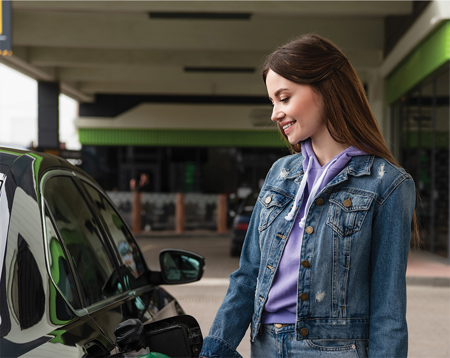A young woman standing beside a car outside a convenience store